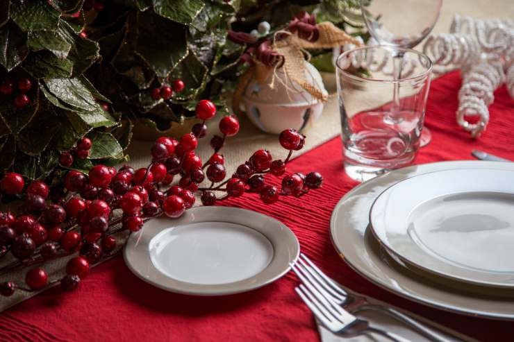 Una tavola apparecchiata con delle bacche rosse tipiche del natale