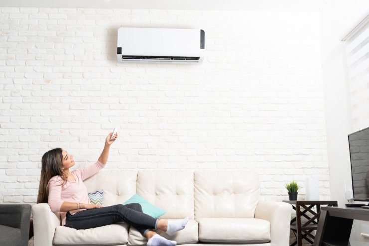Una persona sul divano che imposta la temperatura del condizionatore