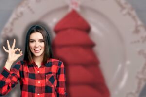 tovagliolo a forma di albero di natale nel piatto e donna sorridente che fa ok con le mani