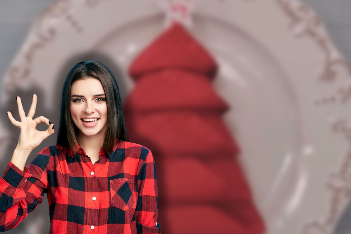 tovagliolo a forma di albero di natale nel piatto e donna sorridente che fa ok con le mani
