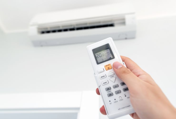 donna con telecomando in mano che imposta condizionatore 
