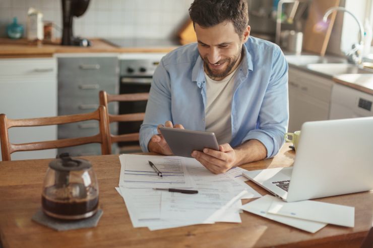 Una persona che osserva documenti cartacei e digitali e sorride