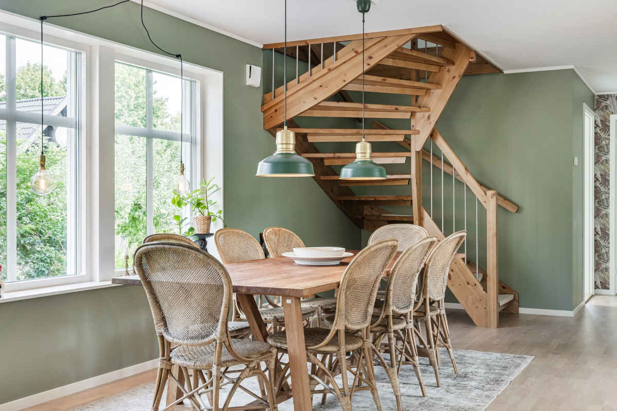 Sala da pranzo in legno con scala angolare e pareti verde salvia
