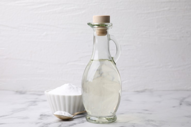 Una foto di un contenitore di bicarbonato ed una boccetta di aceto