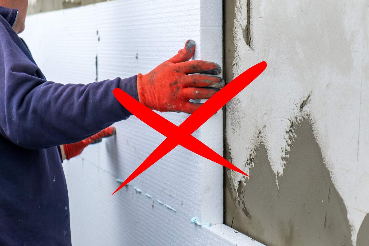 Un uomo che installa un cappotto termico e sopra ci sta una croce rossa