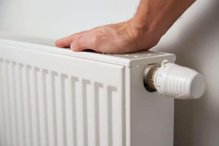 Una persona che sente la temperatura del termosifone con la mano