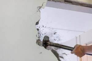 uomo demolisce un muro con un martello