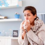 Una donna che sente freddo e si soffia il naso in casa ed un clima ghiacciato