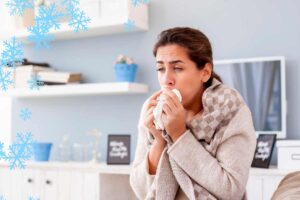 Una donna che sente freddo e si soffia il naso in casa ed un clima ghiacciato