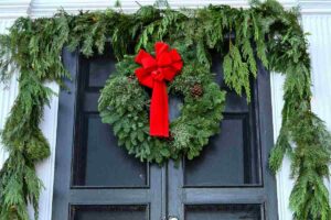 Una porta con decori natalizi e con sopra una ghirlanda