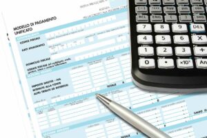 Un documento da compilare con sopra una penna ed una calcolatrice