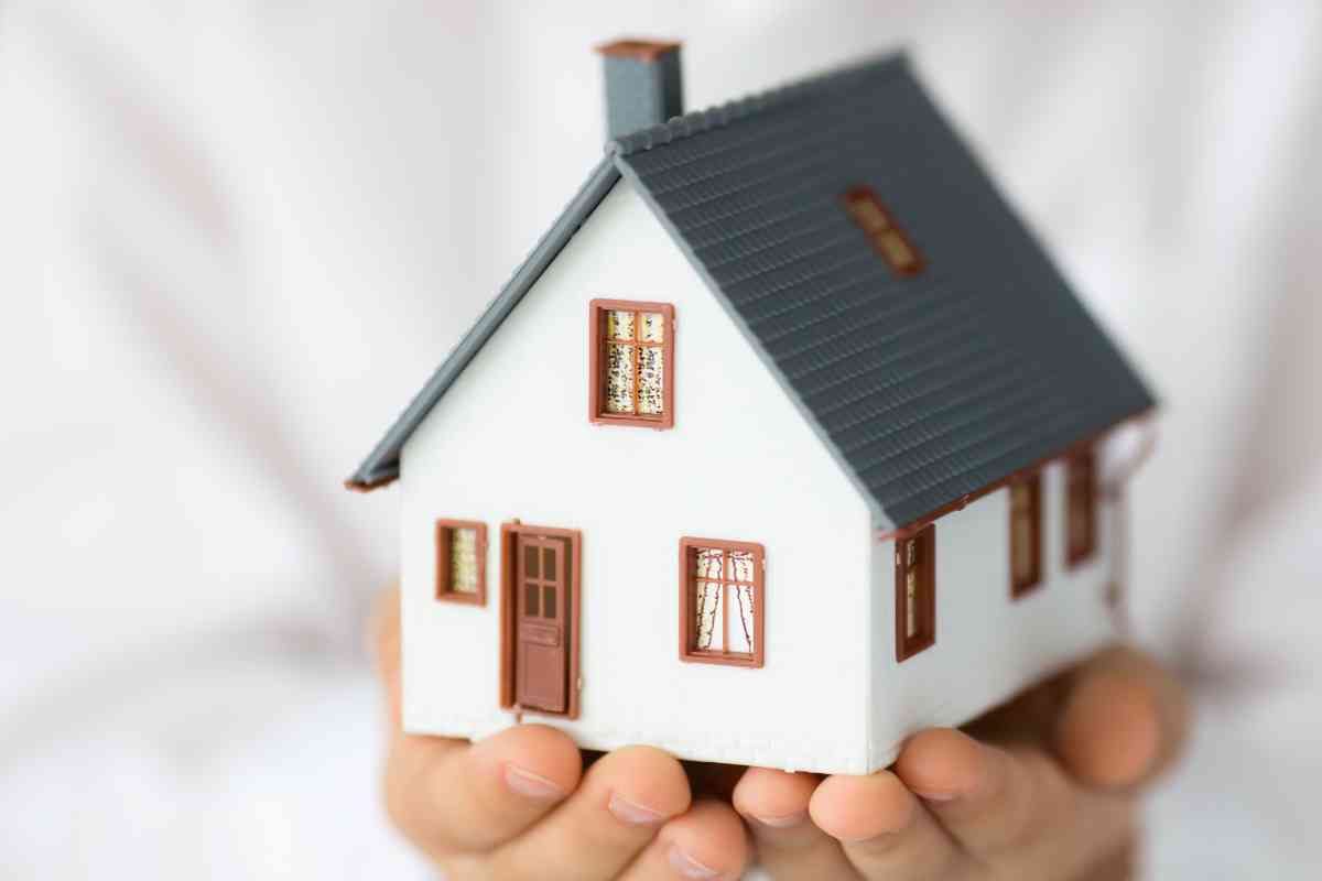 mano sorregge un modellino di casa