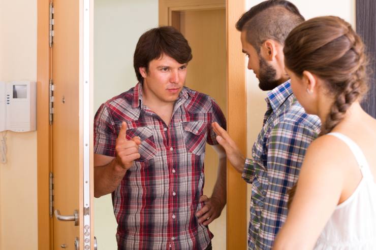 Un uomo alla porta di casa dei suoi vicini che si lamenta.