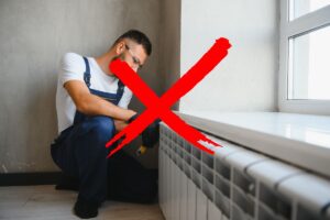 Un operaio che sta smontando un termosifone con una X rossa in primo piano