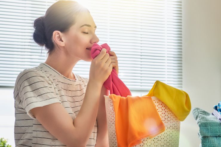 Una donna che annusa felicemente i panni puliti e profumati