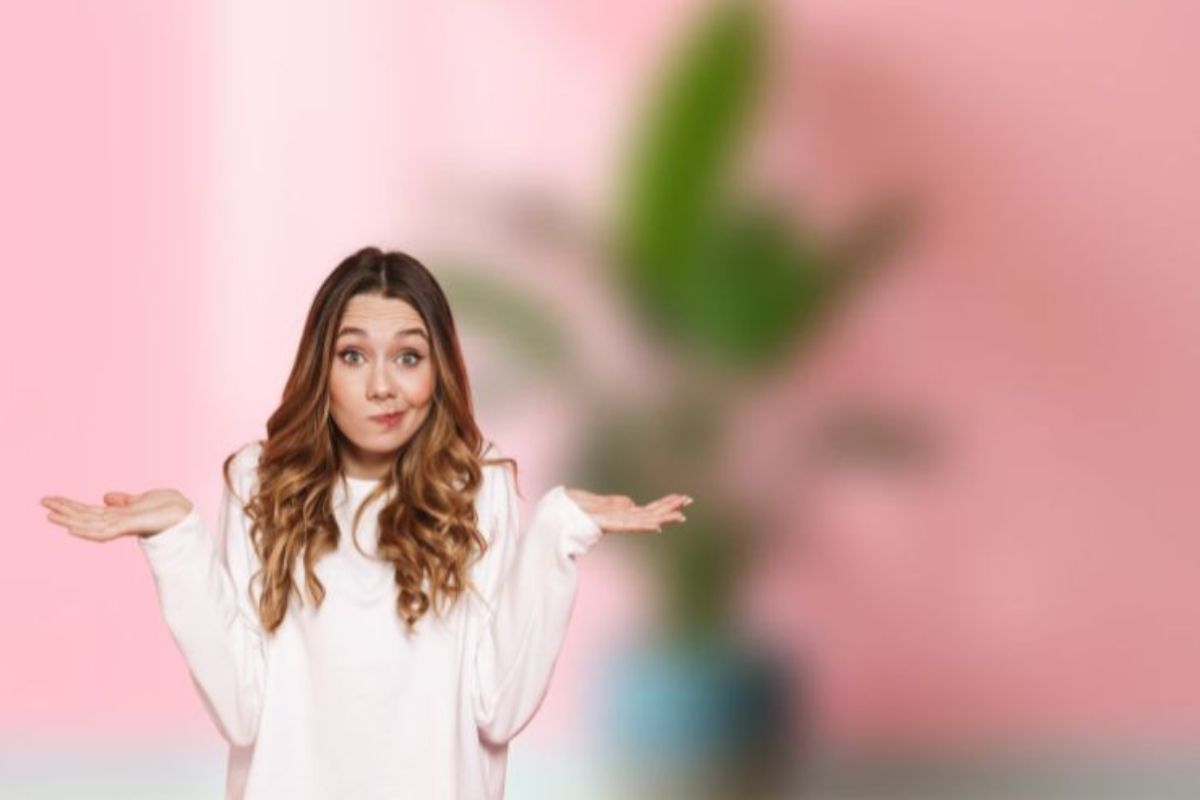 Una foto sfocata di una pianta da casa ed una ragazza in primo piano dubbiosa