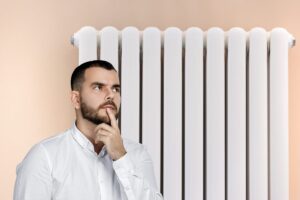 Un termosifone sullo sfondo ed un uomo dubbioso in primo piano pensieroso