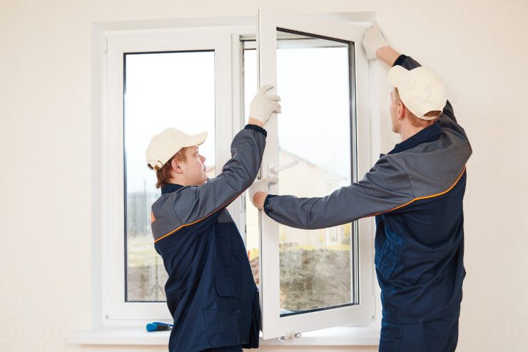 Due operai che si stanno assicurando di montare bene una finestra
