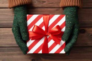un pacchetto di un regalo di natale originale tra due mani che indossano guanti