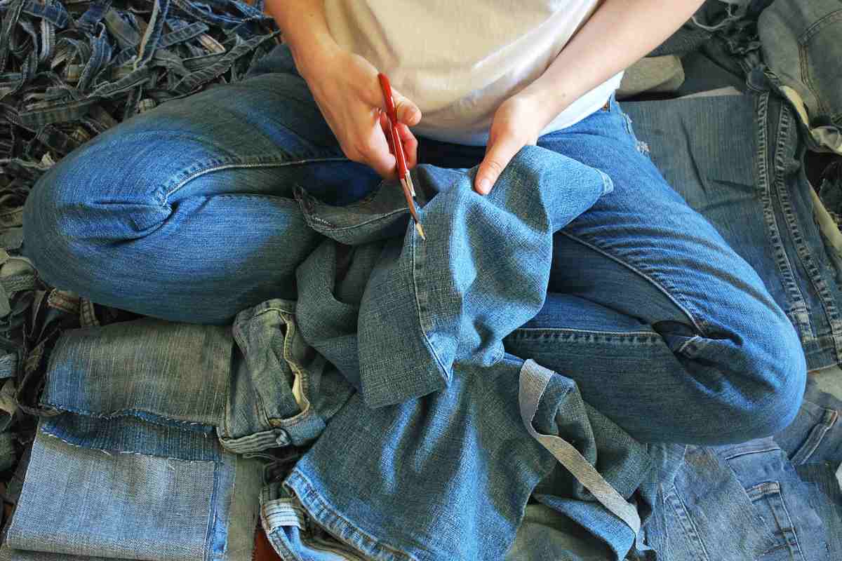 una ragazza con forbici taglia per riutilizzare vecchi jeans