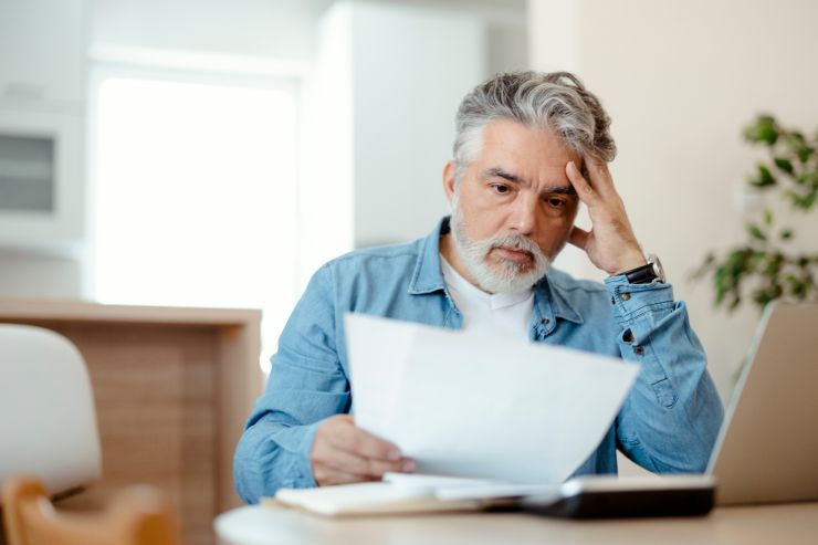 Un uomo che guarda preoccupato un foglio con sopra delle spese