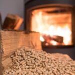 Una stufa a pellet in funzione sullo sfondo e in primo piano il pellet