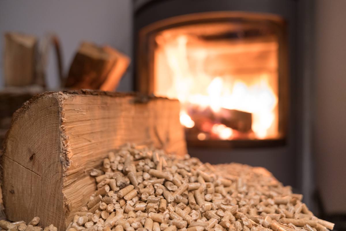 Una stufa a pellet in funzione sullo sfondo e in primo piano il pellet