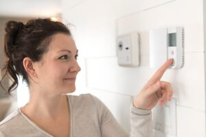 Una donna che spegne i termosifoni tramite un termostato