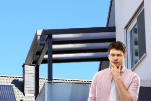 Una tettoia nel balcone di casa ed un uomo in dubbio in primo piano