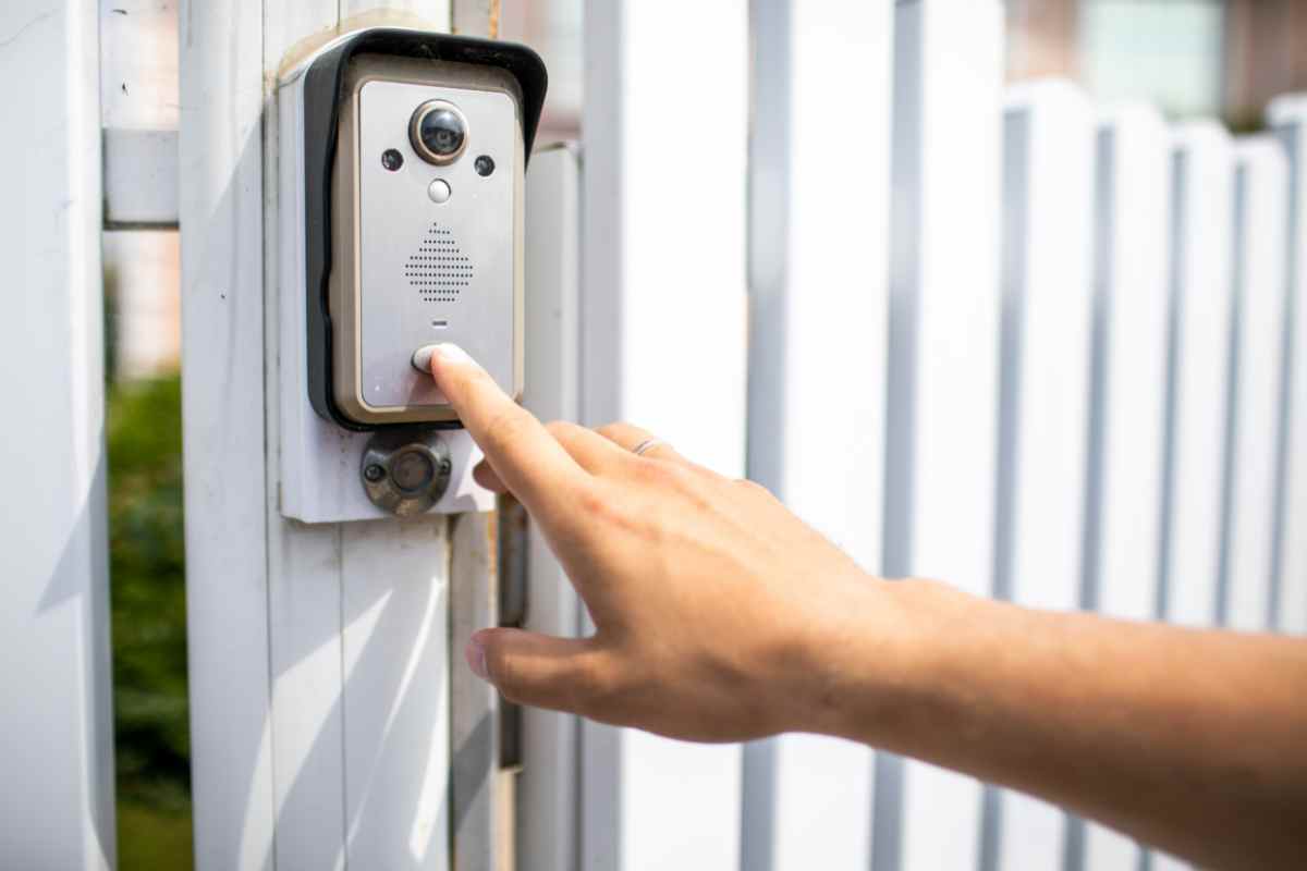 mano sul pulsante del videocitofono connesso in remoto posto su una staccionata