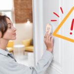 Una donna che imposta i termostati e un segnale in alto a destra di pericolo