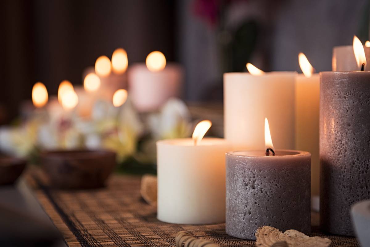 candele bianche e grigie accese su tavola in legno con candele sullo sfondo