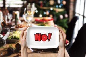 sfondo con una tavola natalizia, in primo piano due mani che reggono un vassoio e scritta no