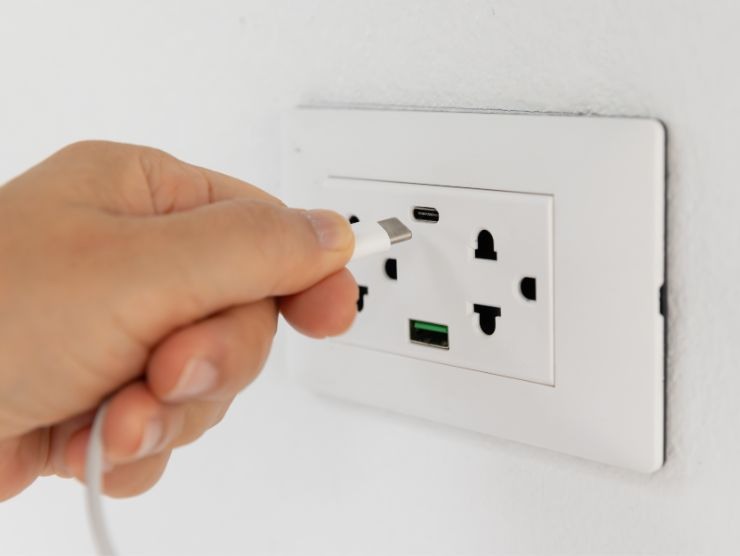 mano che inserisce un cavo usb in una presa al muro