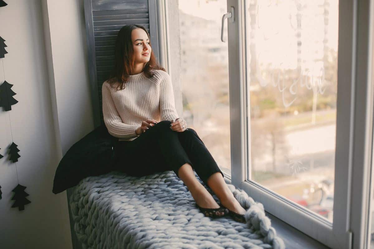 Donna seduta alla finestra con plaid grigio