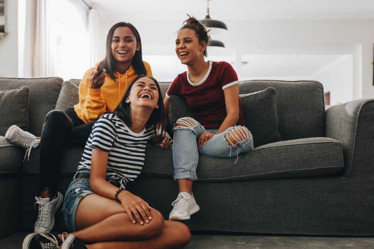 Tre amiche sedute su divano grigio