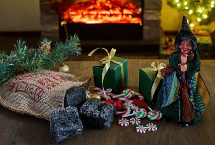 calze piene di dolcetti e befane in miniatura sul tavolo e con camino sullo sfondo