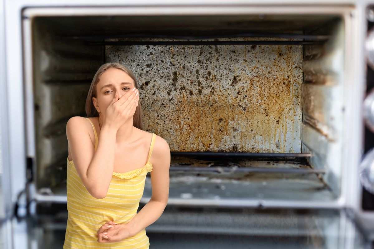 fornetto pieno di sporco e d'incrostazioni e donna in primo piano che si tappa naso e bocca per il disgusto