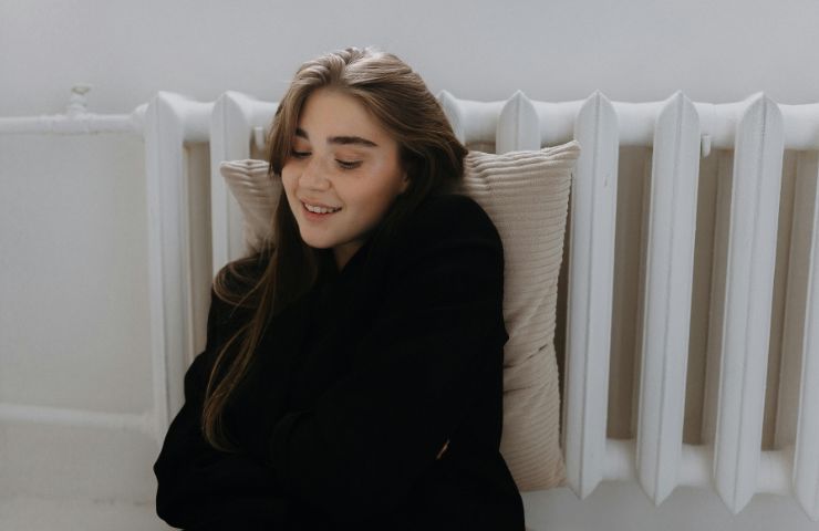 donna accoccolata vicino ai termosifoni