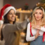 donna sorridente che addobba albero di natale e un'altra che fa stop con le mani