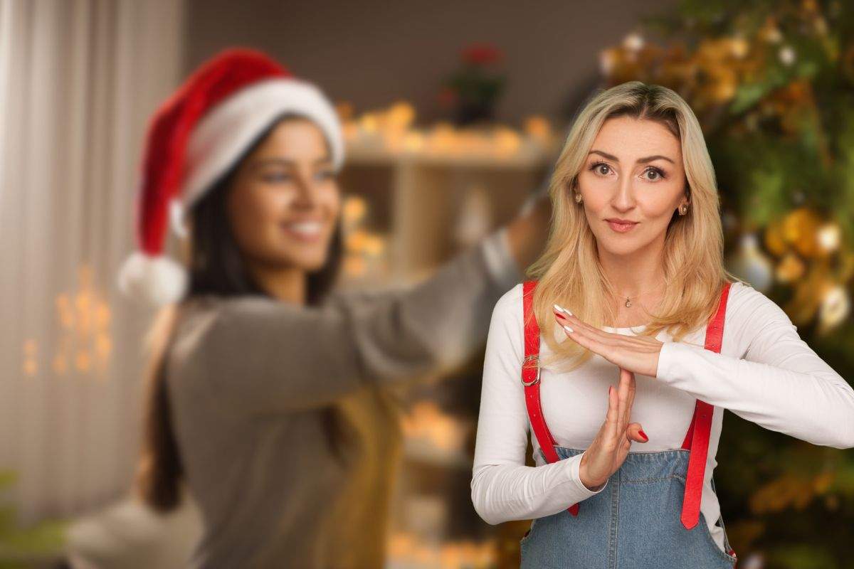 donna sorridente che addobba albero di natale e un'altra che fa stop con le mani