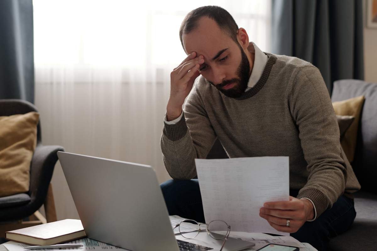 uomo che controlla fogli e pc