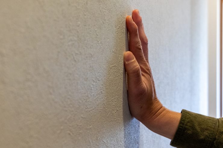 Una persona con una mano su un muro per verificare se è freddo