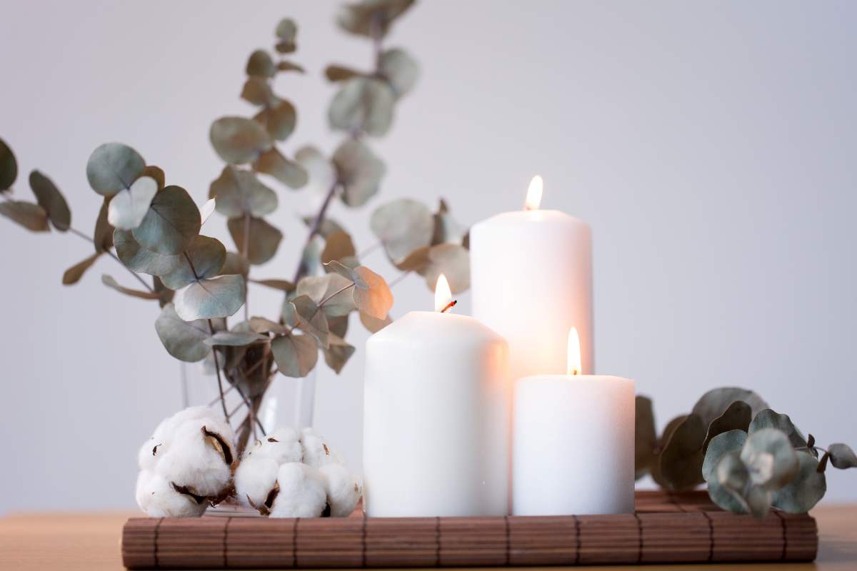 candele bianche con rami verdi e tovaglietta color legno