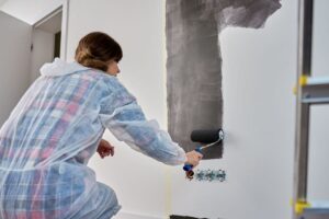 donna che dipinge parete con rullo