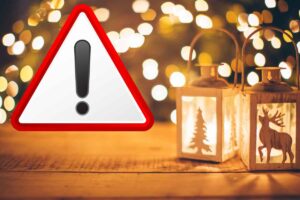 Lanterna con candele accese all’interno su tavolo di legno con luci led sullo sfondo e divieto in primo piano