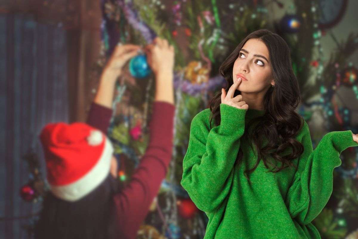donna che addobba albero di natale e un'altra che pensa