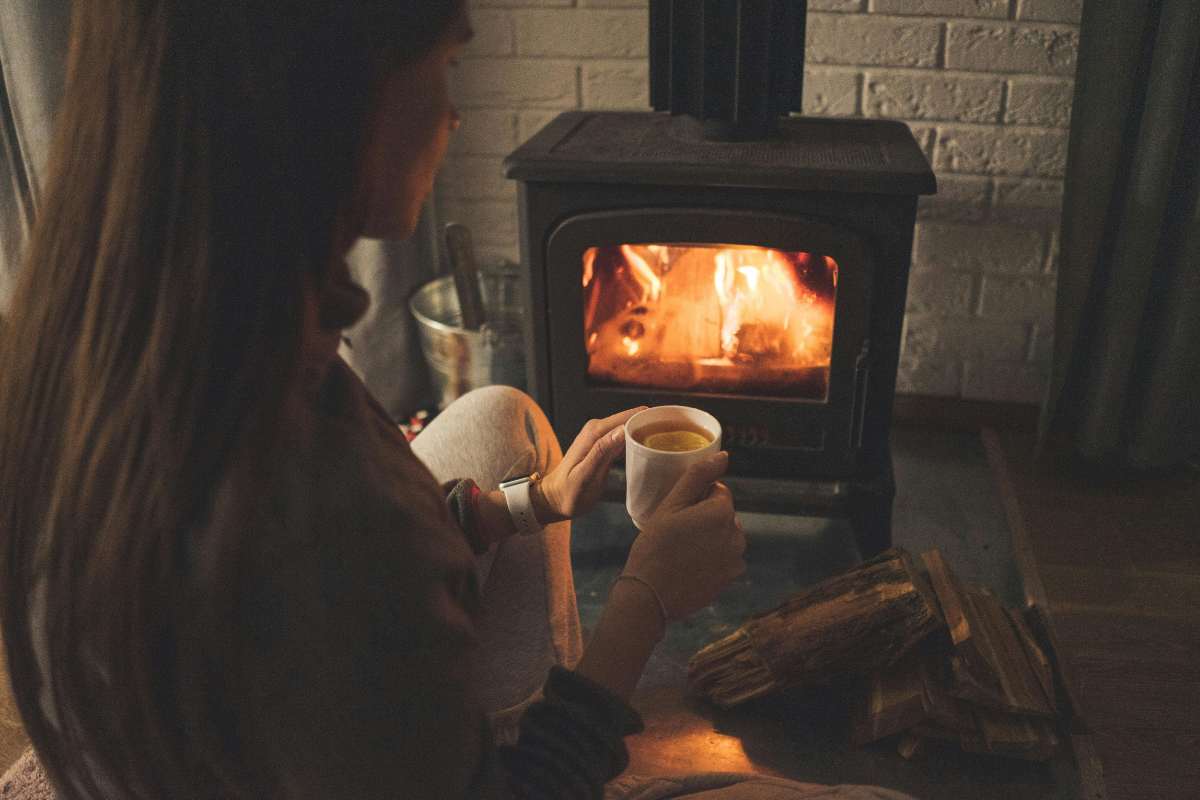 donna davanti al camino acceso con una tazza di te