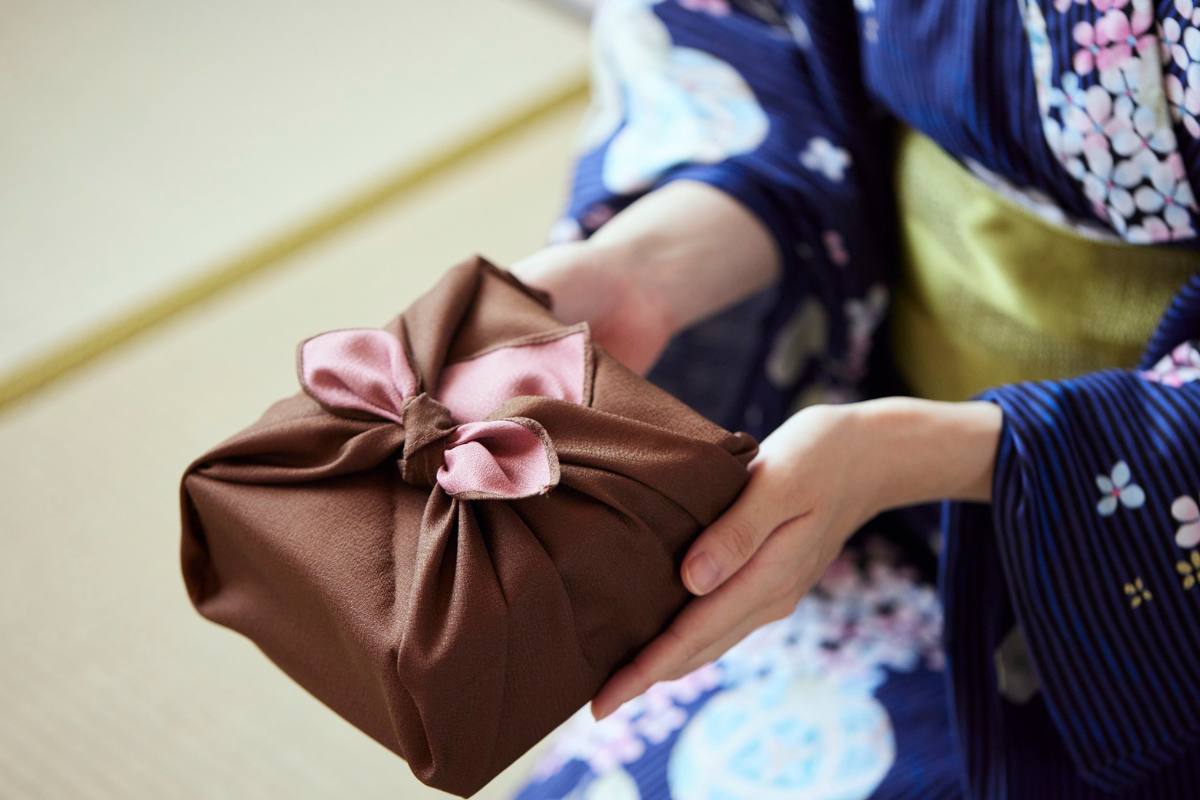 donna con pacchetto marrone fatto con furoshiki