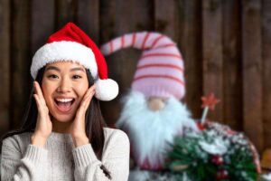 gnomo natalizio sullo sfondo e donna sorpresa con cappello di babbo natale